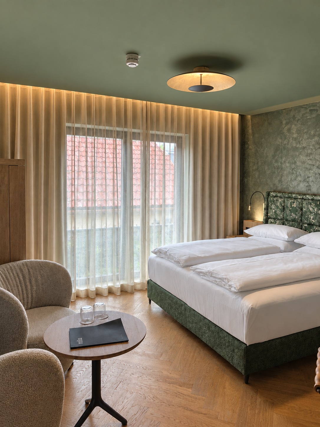 Noa Gästezimmer mit grünen Wänden, Bett und raumhohen Gardinen