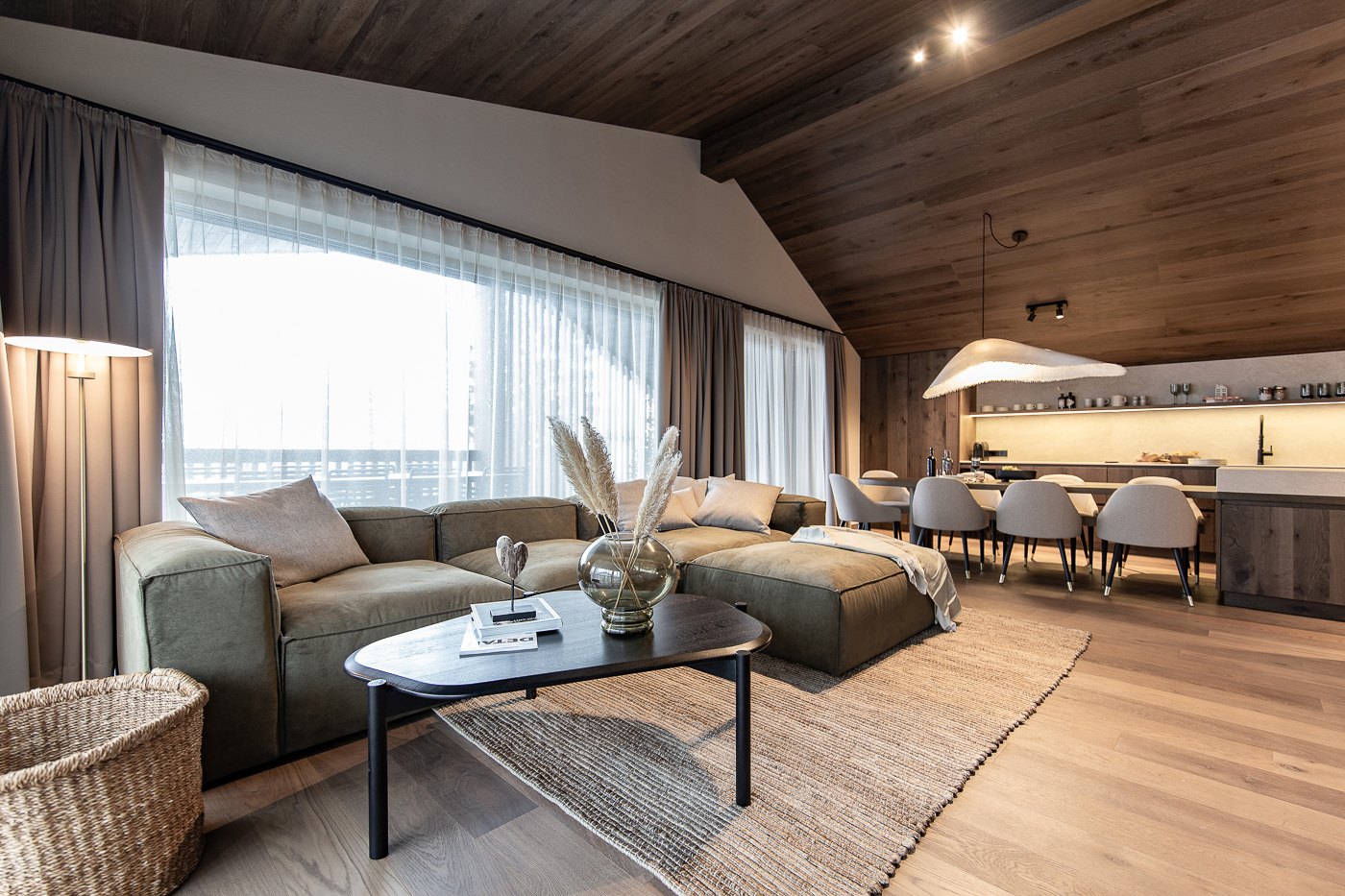 Offener Penthouse-Wohnbereich mit Sofa, Teppich und raumhohen Vorhängen
